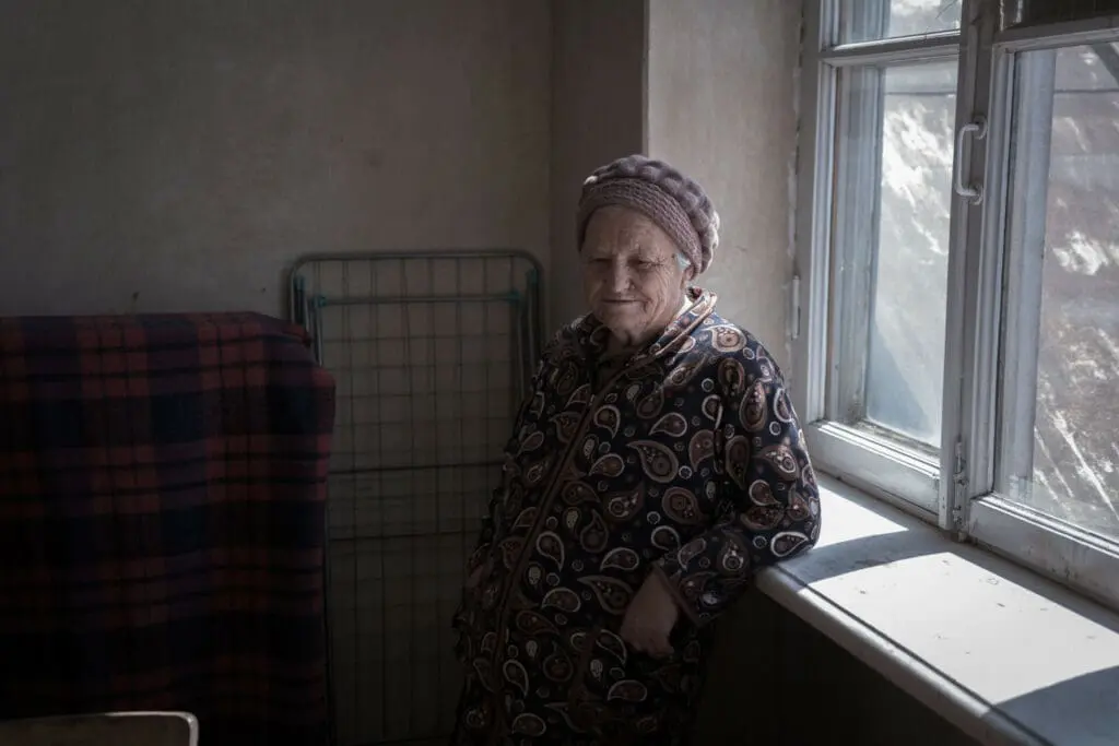 Greta next to the window in her rental house. Due to the inability to afford rent individually, many families have joined together, residing in crowded accommodations. Omar Hamed Beato for Center for International Policy.