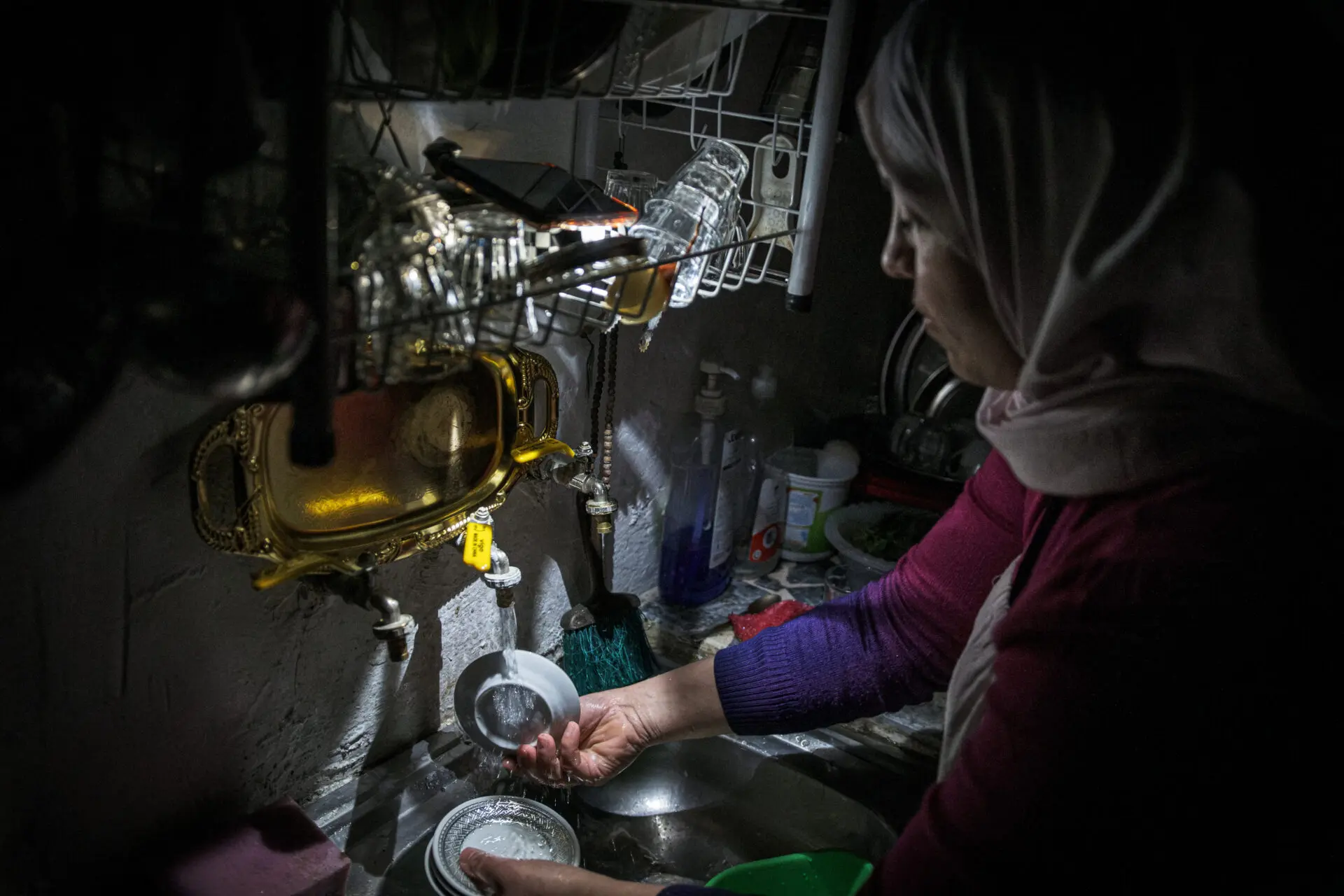 Rania uses her smartphone to light up the kitchen and do the dishes.
